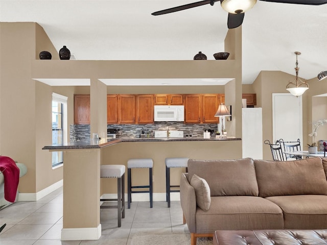 tiled living room featuring ceiling fan and vaulted ceiling