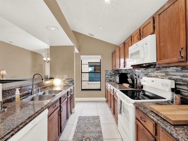 kitchen with lofted ceiling, sink, white appliances, light tile patterned flooring, and hanging light fixtures