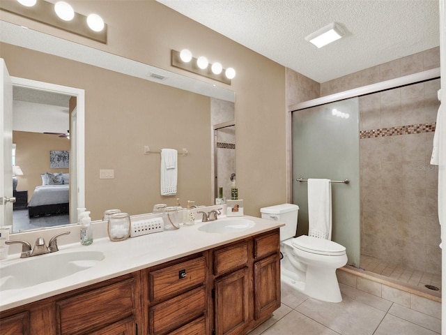 bathroom with a textured ceiling, tile patterned flooring, vanity, toilet, and walk in shower