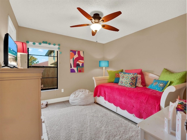 bedroom with a textured ceiling, ceiling fan, and light tile patterned floors