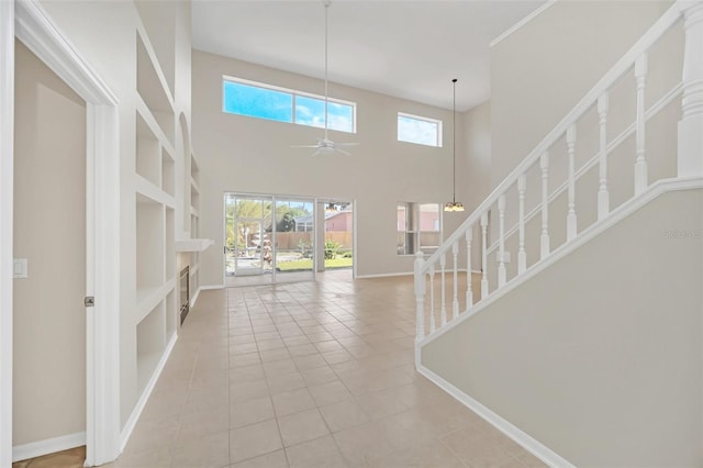 entrance foyer featuring ceiling fan, a healthy amount of sunlight, a towering ceiling, and light tile patterned flooring