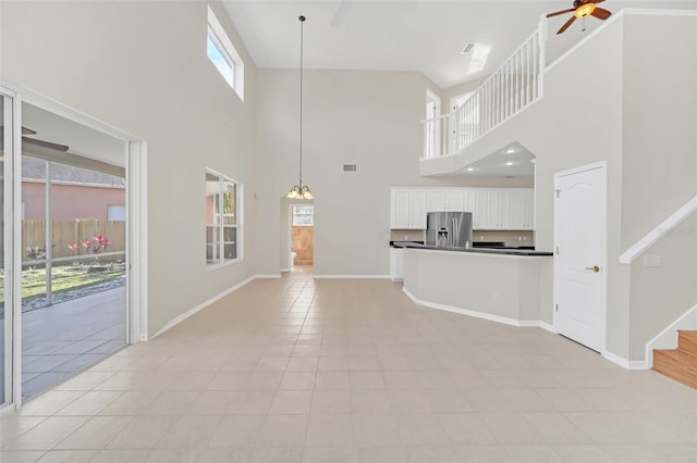 unfurnished living room with a towering ceiling, ceiling fan, and light tile patterned flooring