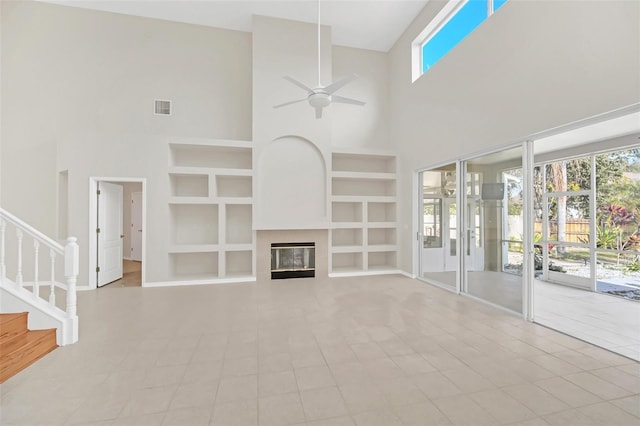 unfurnished living room with ceiling fan, a high ceiling, built in shelves, and light tile patterned floors