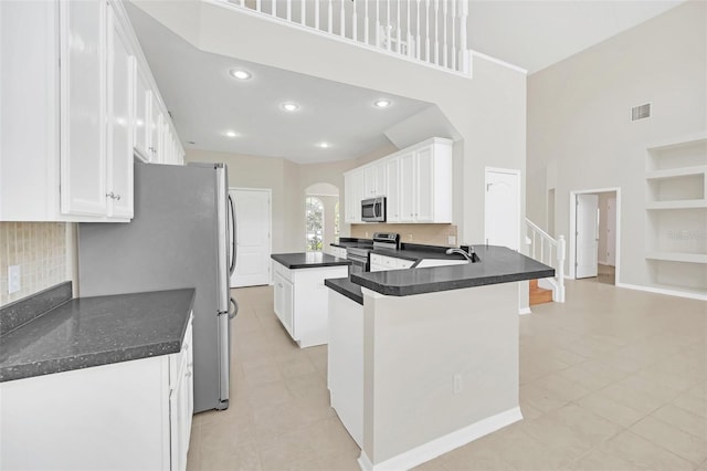 kitchen with built in shelves, white cabinetry, appliances with stainless steel finishes, and kitchen peninsula