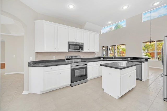 kitchen with a center island, white cabinets, sink, kitchen peninsula, and stainless steel appliances