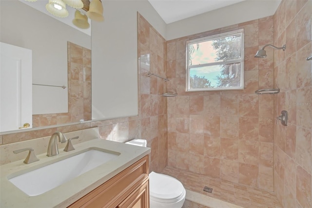 bathroom with vanity, toilet, and tiled shower