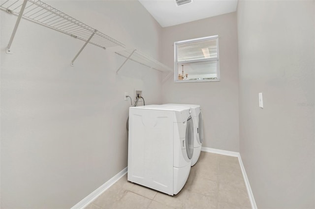 laundry room with independent washer and dryer and light tile patterned flooring