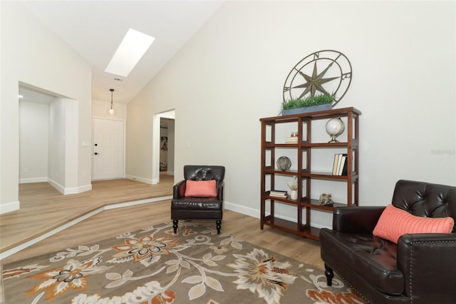 living area featuring wood-type flooring, a skylight, and high vaulted ceiling