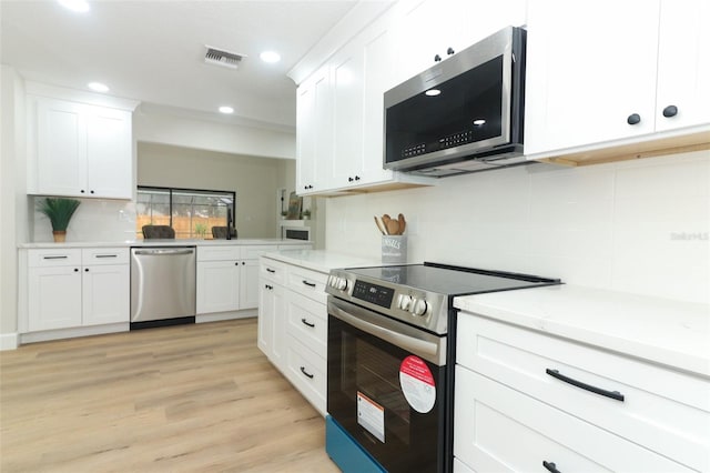 kitchen featuring appliances with stainless steel finishes, light stone countertops, light wood-type flooring, and white cabinets