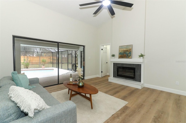 living room featuring light hardwood / wood-style flooring, a fireplace, high vaulted ceiling, and ceiling fan