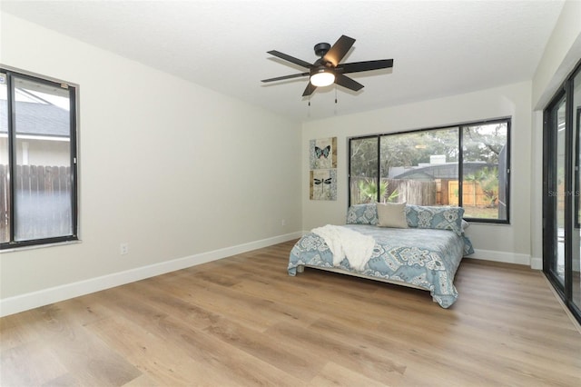 bedroom with ceiling fan, multiple windows, and light wood-type flooring