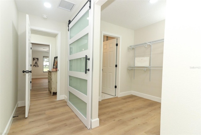 corridor with light hardwood / wood-style floors and a barn door