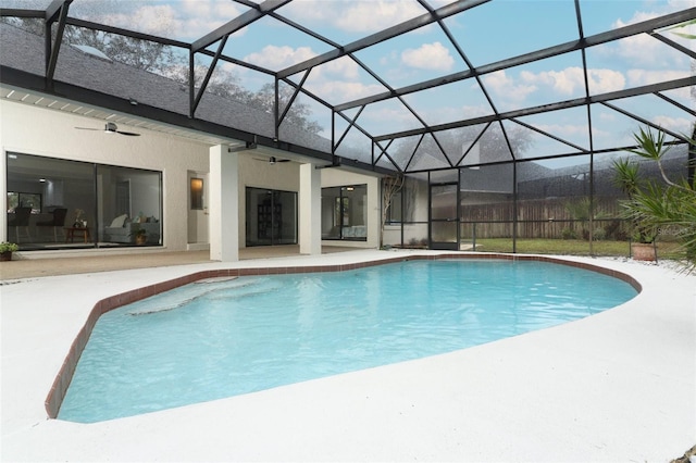 view of swimming pool with ceiling fan, a patio area, and glass enclosure