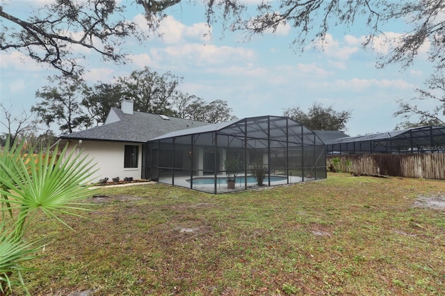 rear view of house featuring a fenced in pool and a yard