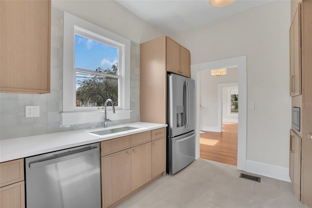 kitchen featuring backsplash, sink, light brown cabinets, and appliances with stainless steel finishes