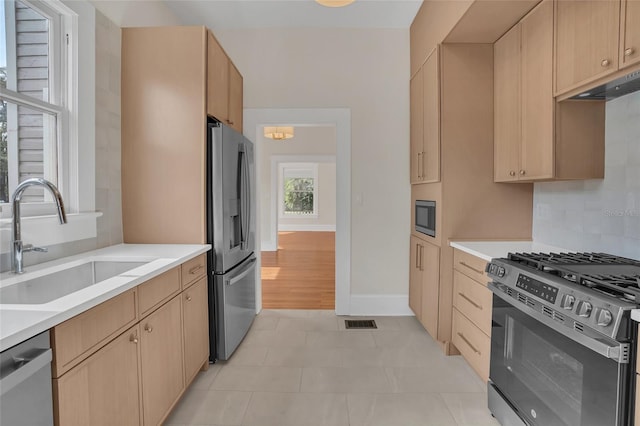 kitchen with decorative backsplash, sink, light brown cabinets, and appliances with stainless steel finishes