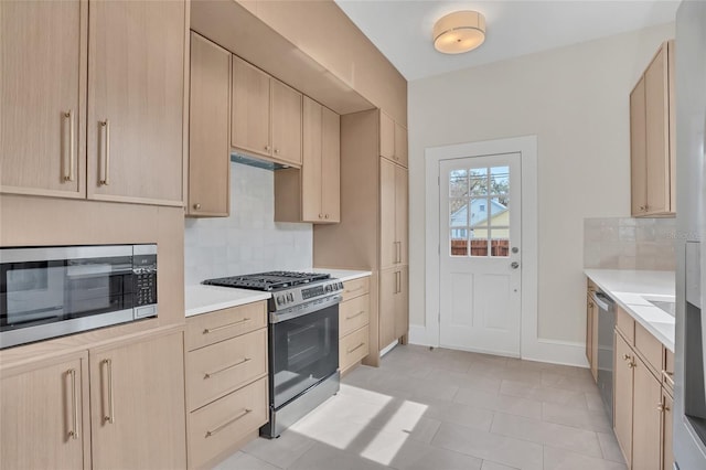 kitchen with light tile patterned flooring, appliances with stainless steel finishes, decorative backsplash, and light brown cabinets