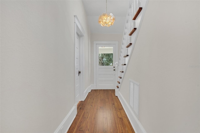 hallway with hardwood / wood-style flooring and a notable chandelier