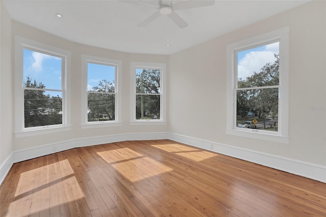 empty room featuring ceiling fan, a healthy amount of sunlight, and wood-type flooring