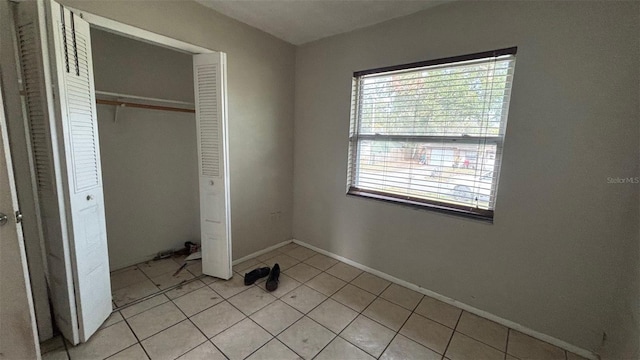 unfurnished bedroom with multiple windows, a closet, and light tile patterned flooring