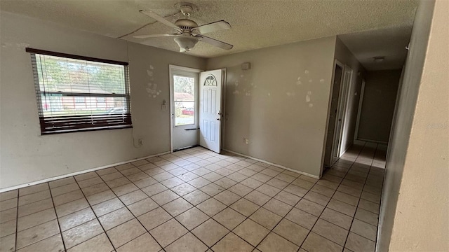 empty room featuring a textured ceiling, ceiling fan, and light tile patterned flooring