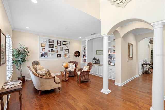 sitting room featuring hardwood / wood-style floors, crown molding, built in features, and decorative columns