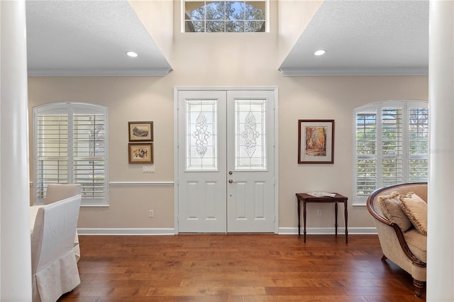 foyer featuring crown molding, dark hardwood / wood-style flooring, a textured ceiling, and french doors