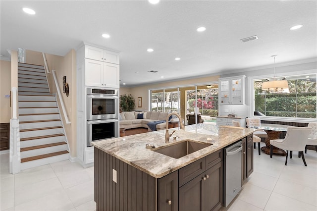 kitchen featuring appliances with stainless steel finishes, white cabinetry, sink, dark brown cabinetry, and light stone countertops