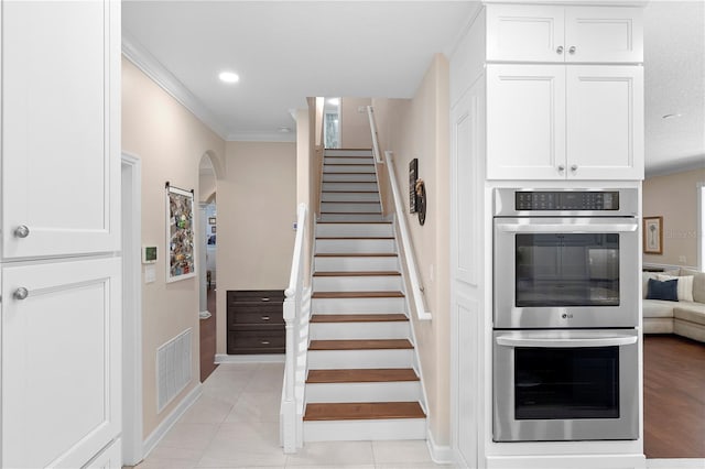 staircase featuring ornamental molding and tile patterned floors