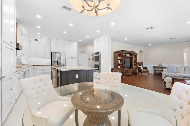 dining area with light tile patterned flooring, ornamental molding, beverage cooler, and a notable chandelier