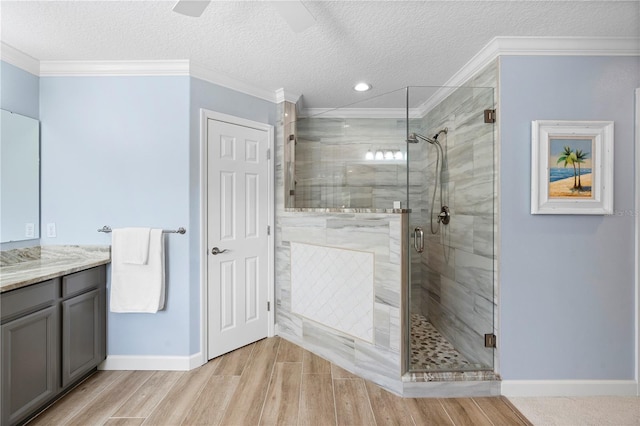 bathroom featuring a shower with shower door, crown molding, a textured ceiling, vanity, and ceiling fan