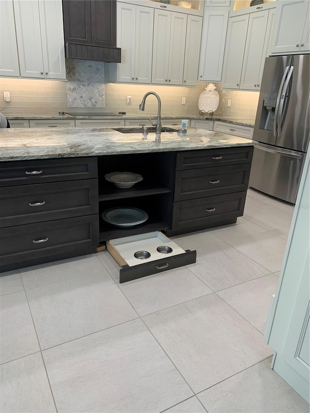 kitchen with white cabinetry, sink, stainless steel fridge with ice dispenser, and light stone counters