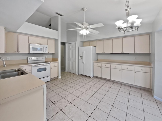 kitchen with sink, white appliances, hanging light fixtures, and lofted ceiling