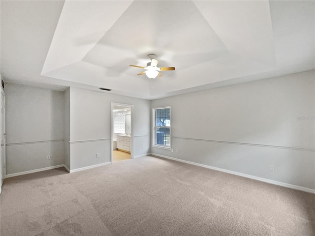 spare room featuring ceiling fan, light colored carpet, and a tray ceiling