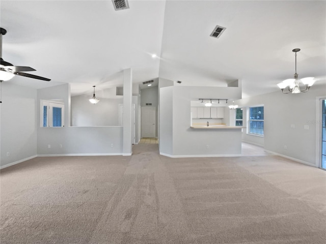 unfurnished living room featuring ceiling fan with notable chandelier, light carpet, and lofted ceiling