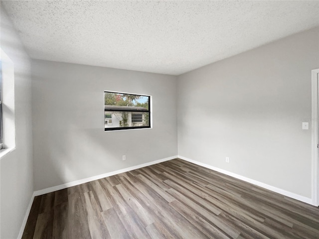 unfurnished room with hardwood / wood-style flooring and a textured ceiling