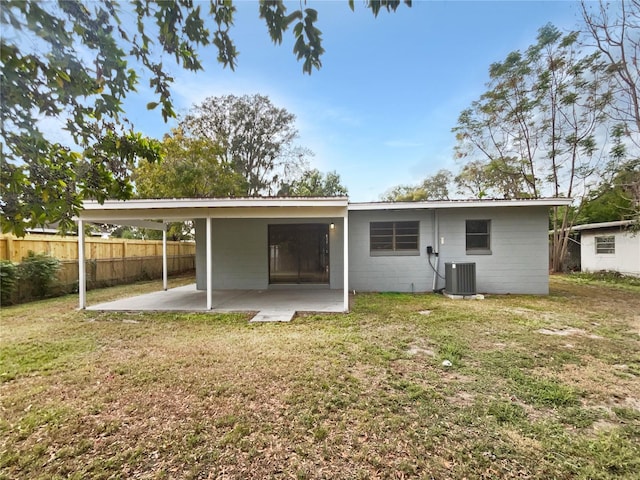 rear view of house with central air condition unit, a patio area, and a lawn