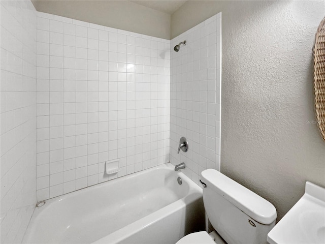 bathroom with toilet and tiled shower / bath combo