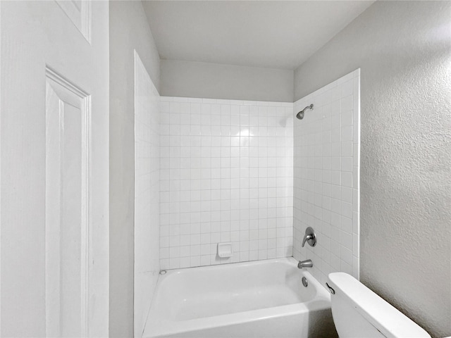 bathroom featuring toilet and tiled shower / bath