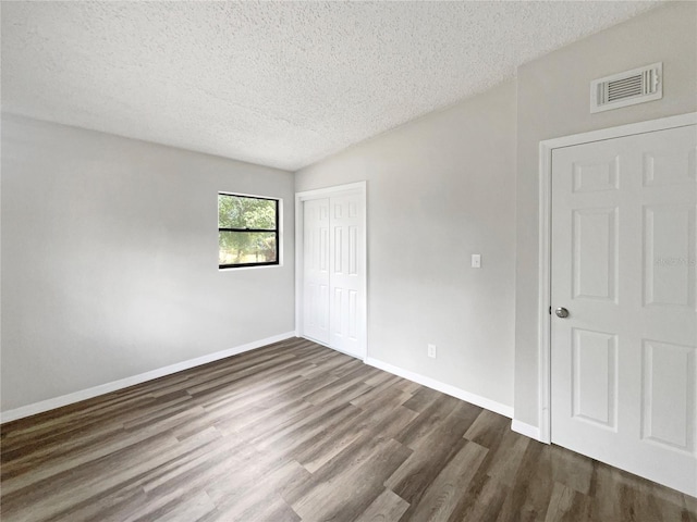 spare room with dark wood-type flooring and a textured ceiling