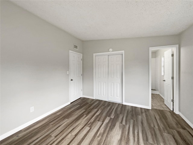 unfurnished bedroom with a textured ceiling, a closet, and dark hardwood / wood-style floors