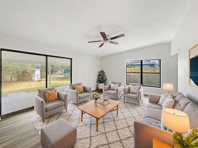 living room featuring light wood-type flooring, a textured ceiling, and ceiling fan