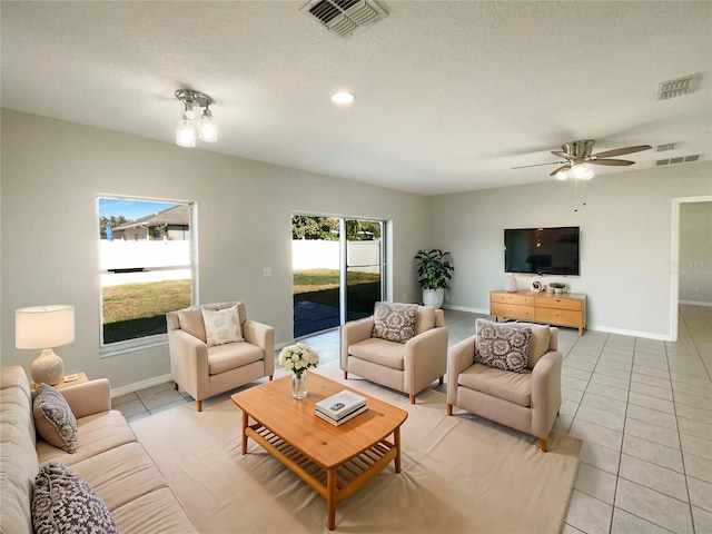 tiled living room with ceiling fan, plenty of natural light, and a textured ceiling