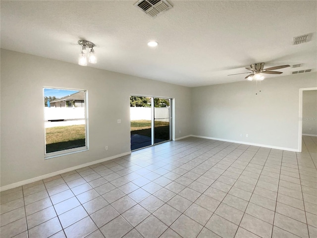 unfurnished room with ceiling fan, a textured ceiling, light tile patterned floors, and a healthy amount of sunlight