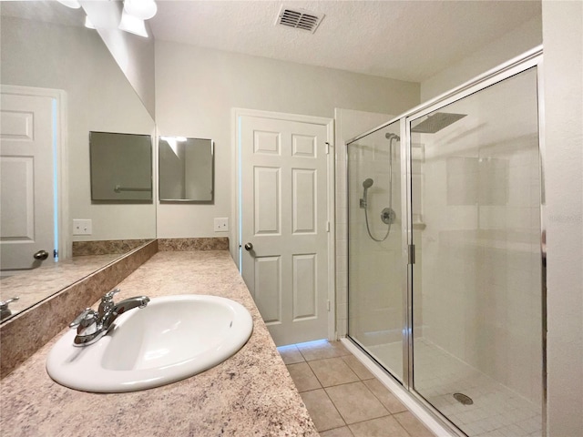 bathroom with a textured ceiling, tile patterned floors, vanity, and an enclosed shower