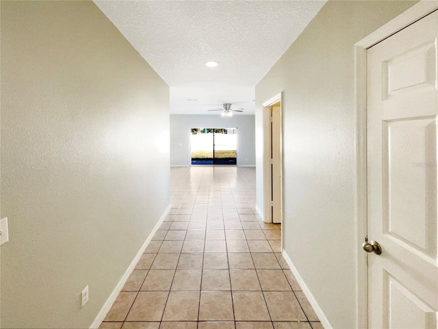 hall featuring a textured ceiling and light tile patterned floors