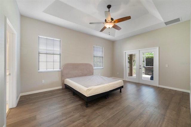 bedroom featuring ceiling fan, dark hardwood / wood-style floors, a tray ceiling, access to exterior, and french doors