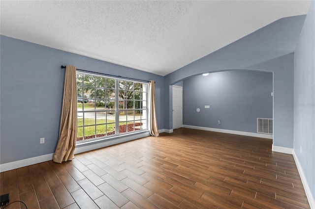 unfurnished room with vaulted ceiling and a textured ceiling