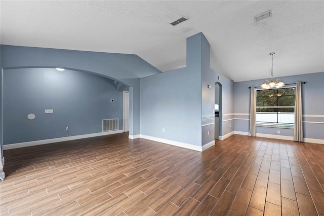 unfurnished living room with lofted ceiling, a notable chandelier, and a textured ceiling