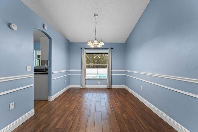 unfurnished dining area with a notable chandelier, dark wood-type flooring, sink, and a textured ceiling